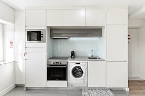Uma cozinha compacta com forno embutido, micro-ondas e máquina de lavar.