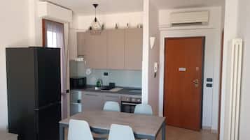 A compact kitchen with a refrigerator, microwave, sink, and dining area with chairs.