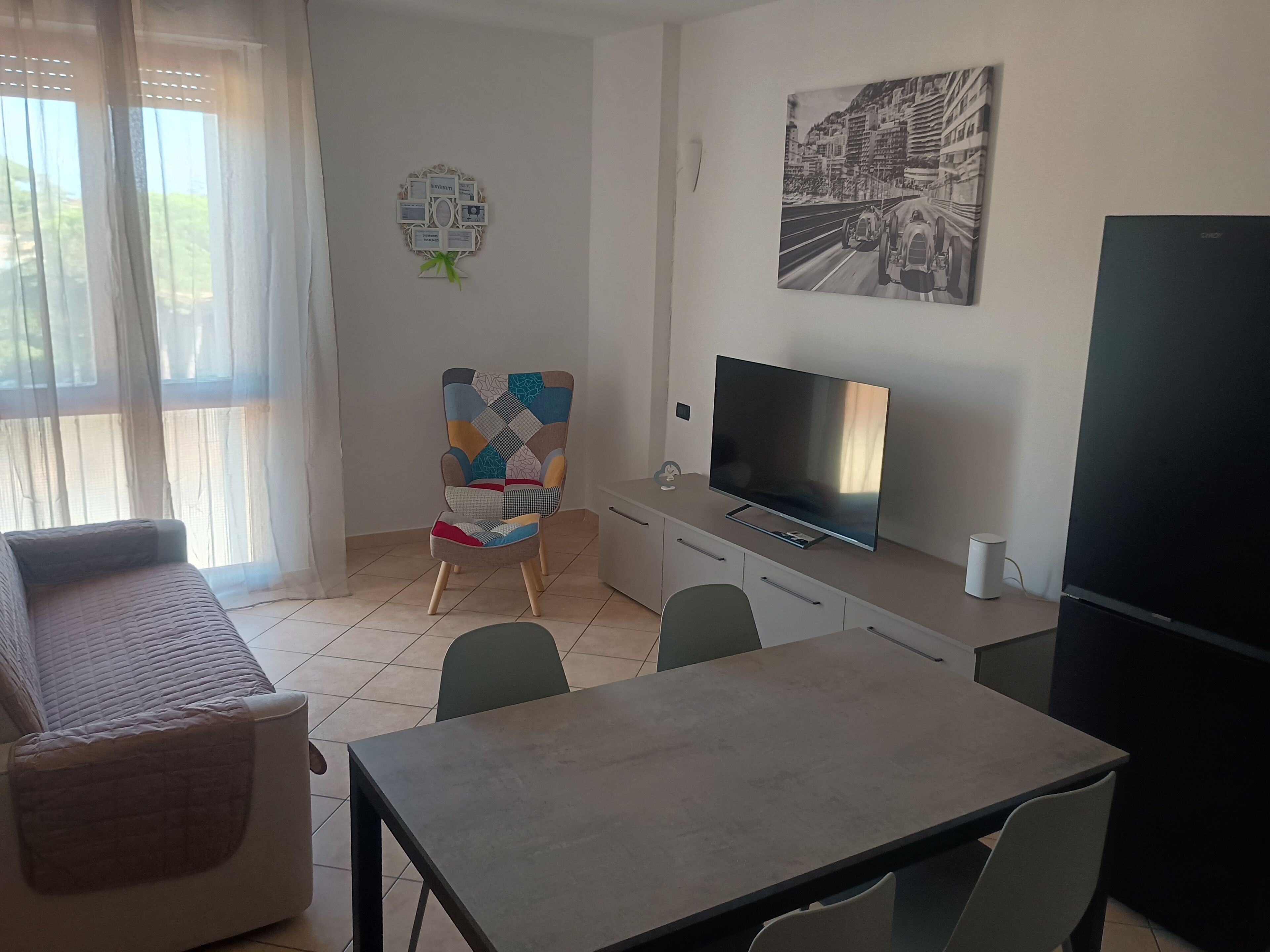 Una sala de estar moderna con sofá, una mesa de comedor, televisor y un cuadro en la pared.