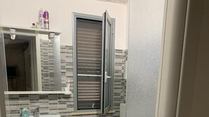 Un baño con lavamanos, inodoro y ventana con persianas.