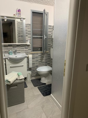 Ein Badezimmer mit Waschbecken, Toilette und einem Fenster mit Jalousien.