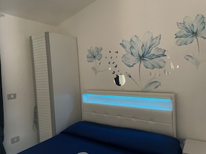 A bedroom with a bed, a wardrobe, and a wall with floral and butterfly decals.