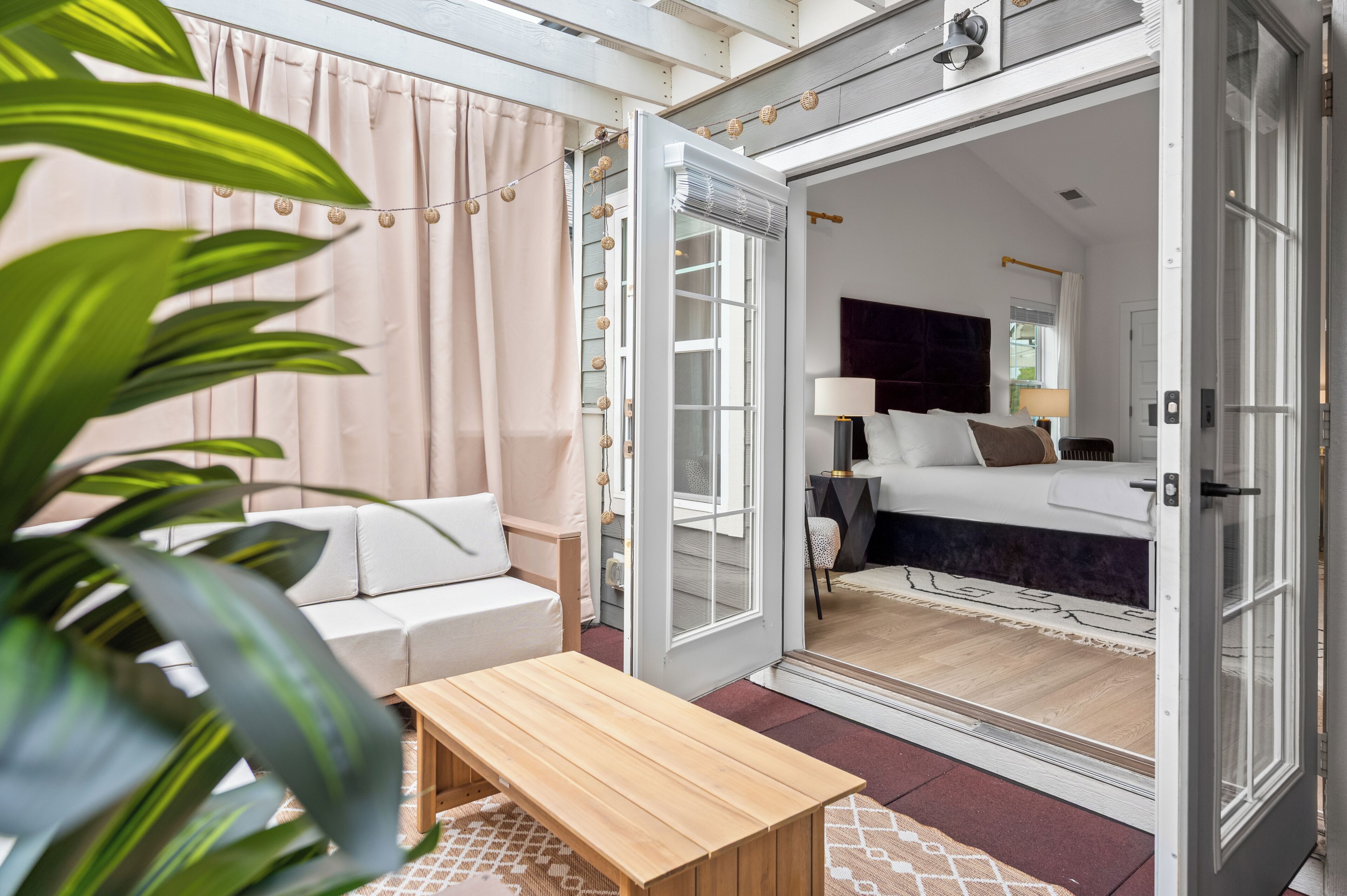 A modern bedroom with a bed, bedside table, and a view through an open door.