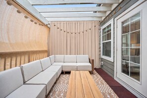 A covered patio with a sectional sofa, a wooden table, and a patterned rug. - Luxurious Townhome in the Nations w/ Penthouse style top floor & walkout balcony (Nashville)