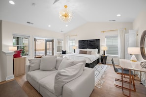 A modern bedroom with a large bed, a sofa, a desk, and a chandelier. - Luxurious Townhome in the Nations w/ Penthouse style top floor & walkout balcony (Nashville)