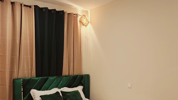 Ein Schlafzimmer mit einem Bett, einem Nachttisch, einem Deckenventilator und einer Wandleuchte.
