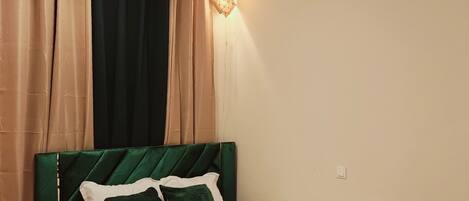 A bedroom with a bed, a nightstand, a ceiling fan, and a wall-mounted light fixture.