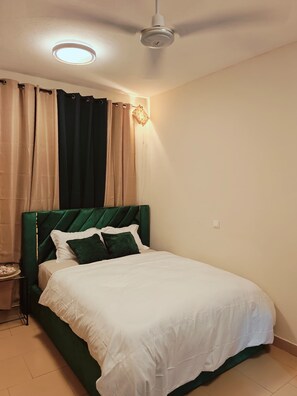 Ein Schlafzimmer mit einem Bett, einem Nachttisch, einem Deckenventilator und einer Wandleuchte.