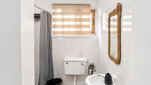 Ein kleines Badezimmer mit Toilette, Waschbecken und Duschvorhang.
