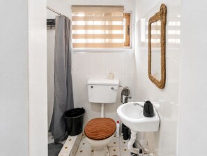 Een kleine badkamer met toilet, wastafel en douchegordijn.