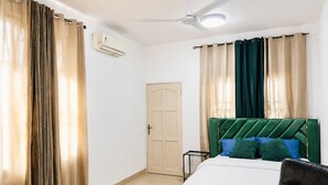 Ein Schlafzimmer mit Bett, Stuhl, Tür und Vorhängen.