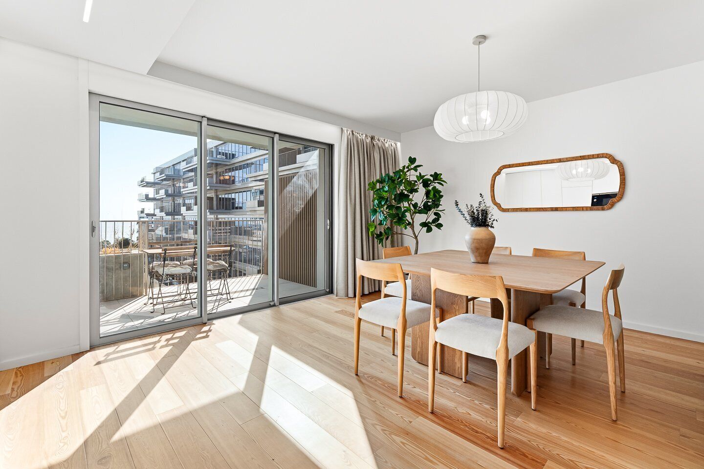 A modern interior with a dining area, a large window, and a view of a building.