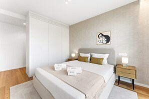 Ein modernes Hotelzimmer mit Bett, Nachttischen, einem Schrank und einem an der Wand befestigten Kunstwerk.