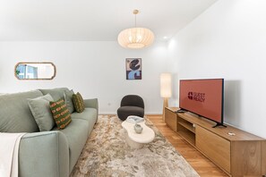 A modern living room with a sofa, a television, a lamp, and a rug. - GuestReady - Luxury apartment with sea view (Vila Nova de Gaia)