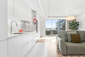 Een moderne keuken met witte kastjes, een roestvrijstalen spoelbak en een rode brandblusser.