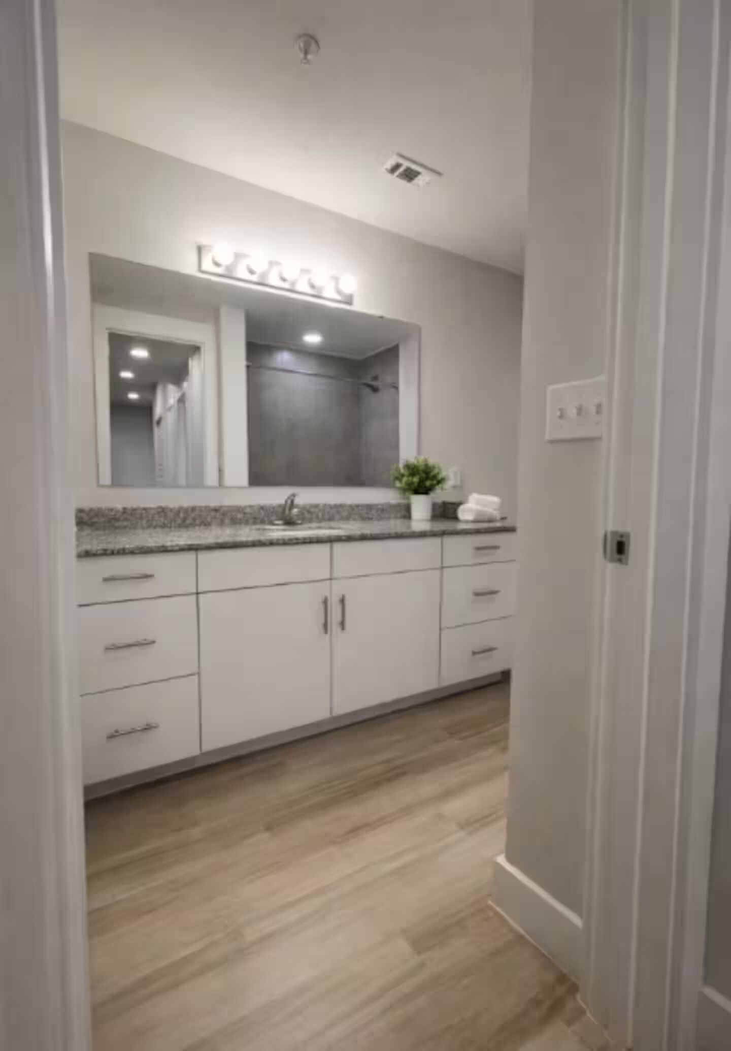 A modern bathroom with a large mirror, a sink, and cabinets.