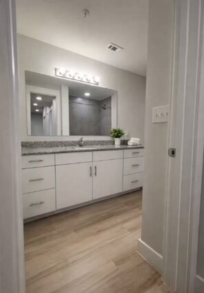 Un baño moderno con un espejo grande, un lavamanos y armarios.