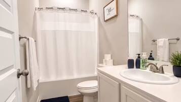 A bathroom with a toilet, a sink, a mirror, and a shower curtain.