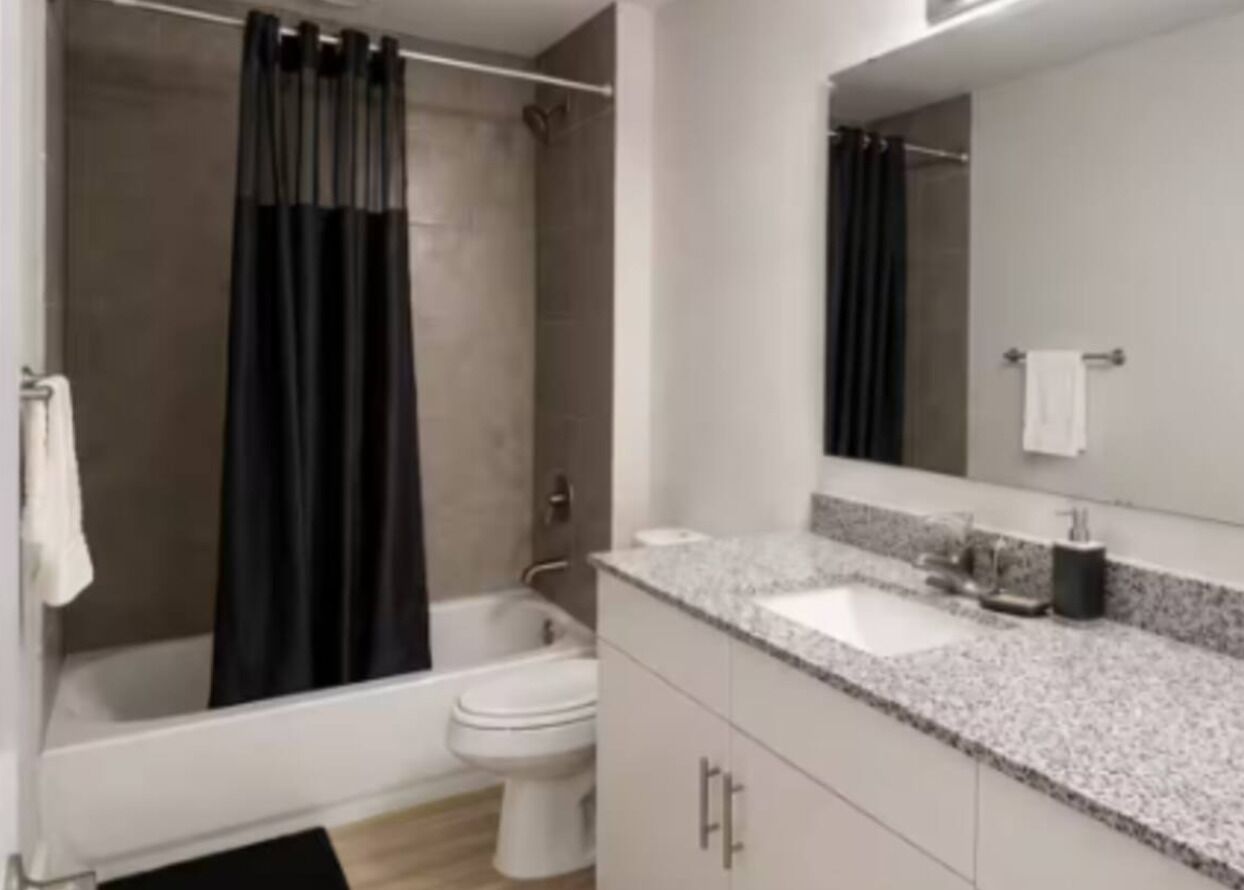 A modern bathroom with a bathtub, toilet, and a large mirror.