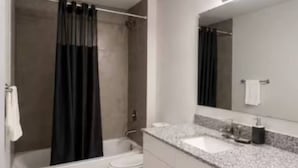 A modern bathroom with a bathtub, toilet, and a large mirror.