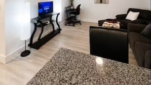 A living room with a flat-screen TV, a ceiling fan, a coffee table, and a sofa.