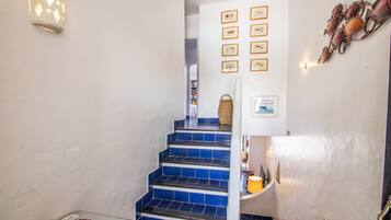 Un escalier recouvert de carreaux bleus mène à une pièce dont les murs sont ornés de tableaux encadrés.