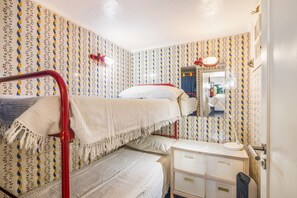 Habitación con literas, espejo, mesita de noche y lámpara roja.