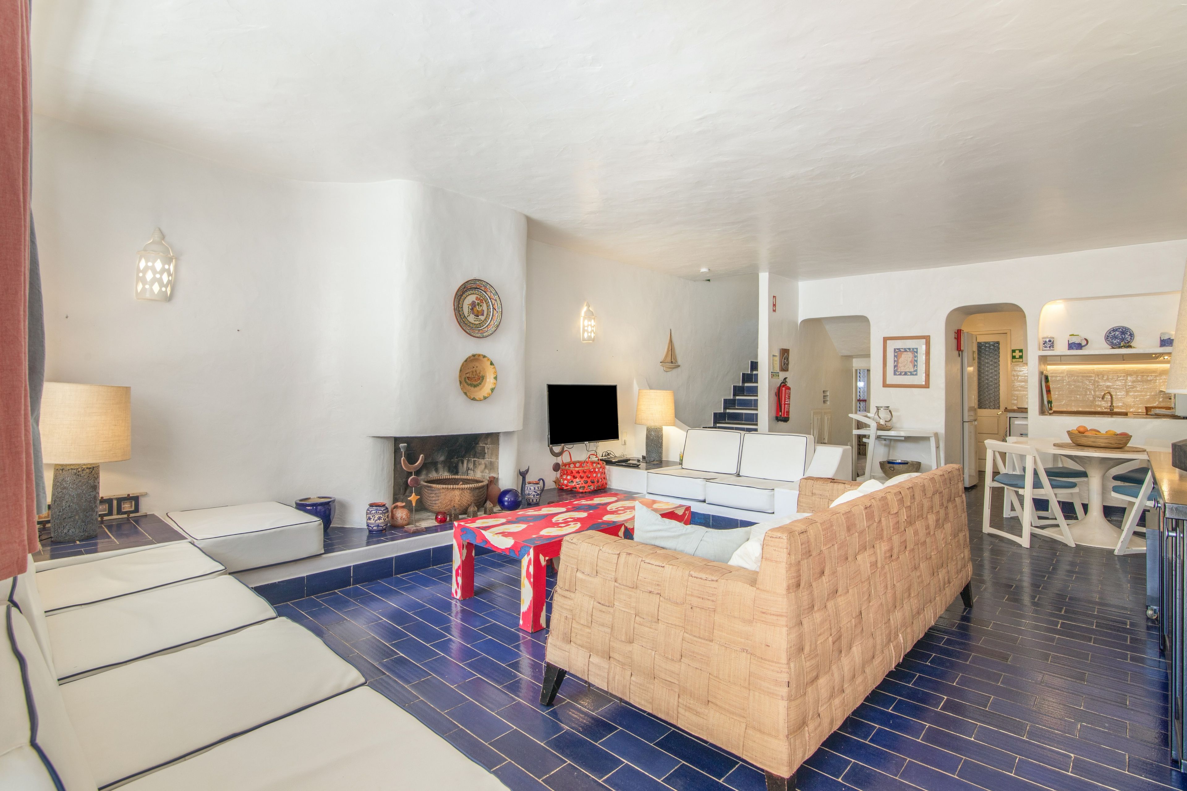 Un salon comprenant un canapé, un téléviseur et un coin repas avec une table et des chaises.