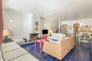 Una sala de estar con un sofá, un televisor y un comedor con mesa y sillas.