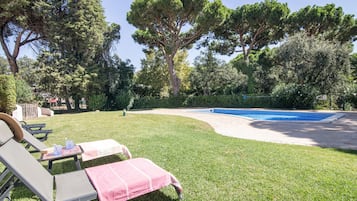 Un jardin avec une piscine, des chaises longues et une pelouse verdoyante.