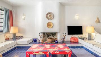 Een woonkamer met een open haard, zitplaatsen, een flatscreen televisie en decoratieve accessoires.