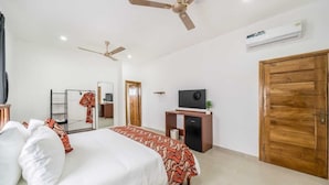 A hotel room with a bed, a television, a wardrobe, and a ceiling fan. - Crown Luxury Apartments  (Kokrobite)