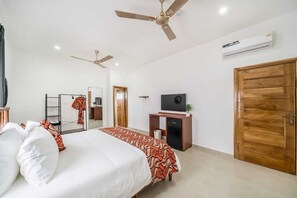 Une chambre d’hôtel équipée d’un lit, d’une télévision, d’une armoire et d’un ventilateur de plafond.