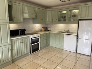 A kitchen with light green cabinets, a white refrigerator, a stove, and a dishwasher. - Lismore Cottage, located in the Heritage town of Lismore (Lismore)
