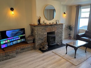 A living room with a stone fireplace, a flat-screen TV, a leather sofa, and a large mirror.