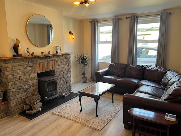 A living room with a stone fireplace, leather sofa, and a large mirror. - Lismore Cottage, located in the Heritage town of Lismore (Lismore)