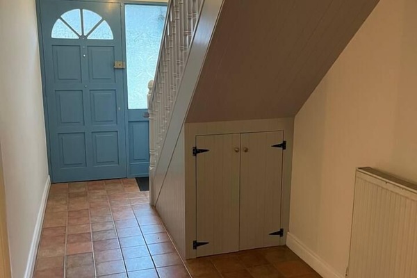 Bright entry hall with charming blue door and handy under-stair storage