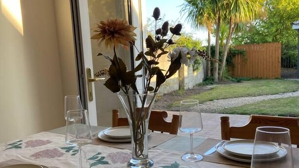 Een eettafel gedekt voor vier personen met uitzicht op een tuin door een glazen deur.
