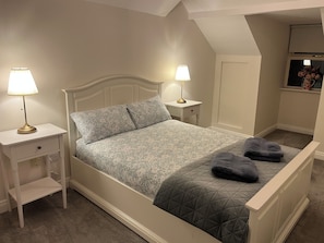 A bedroom with a bed, two bedside tables with lamps, a nightstand, and a window with a view. - Lismore Cottage, located in the Heritage town of Lismore (Lismore)
