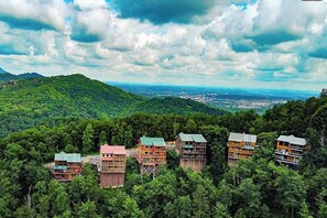 A cluster of multi-story buildings with balconies, surrounded by dense forest, overlooking a valley. - Mountain View Retreat 🏔️ Private Hot Tub, Arcade Room, Steps to Pigeon Forge Fun (Pigeon Forge)
