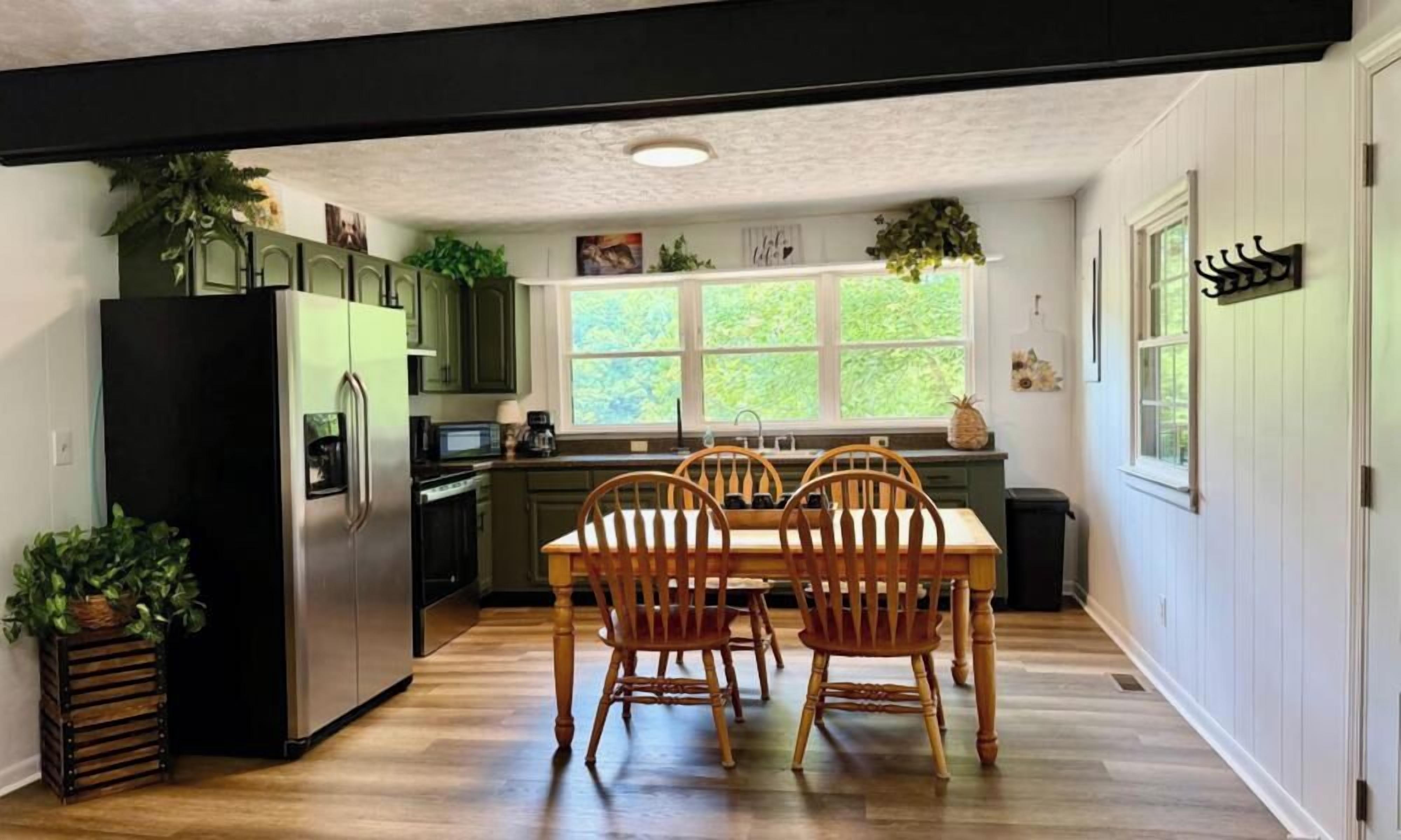A kitchen with a dining table, chairs, and a refrigerator.