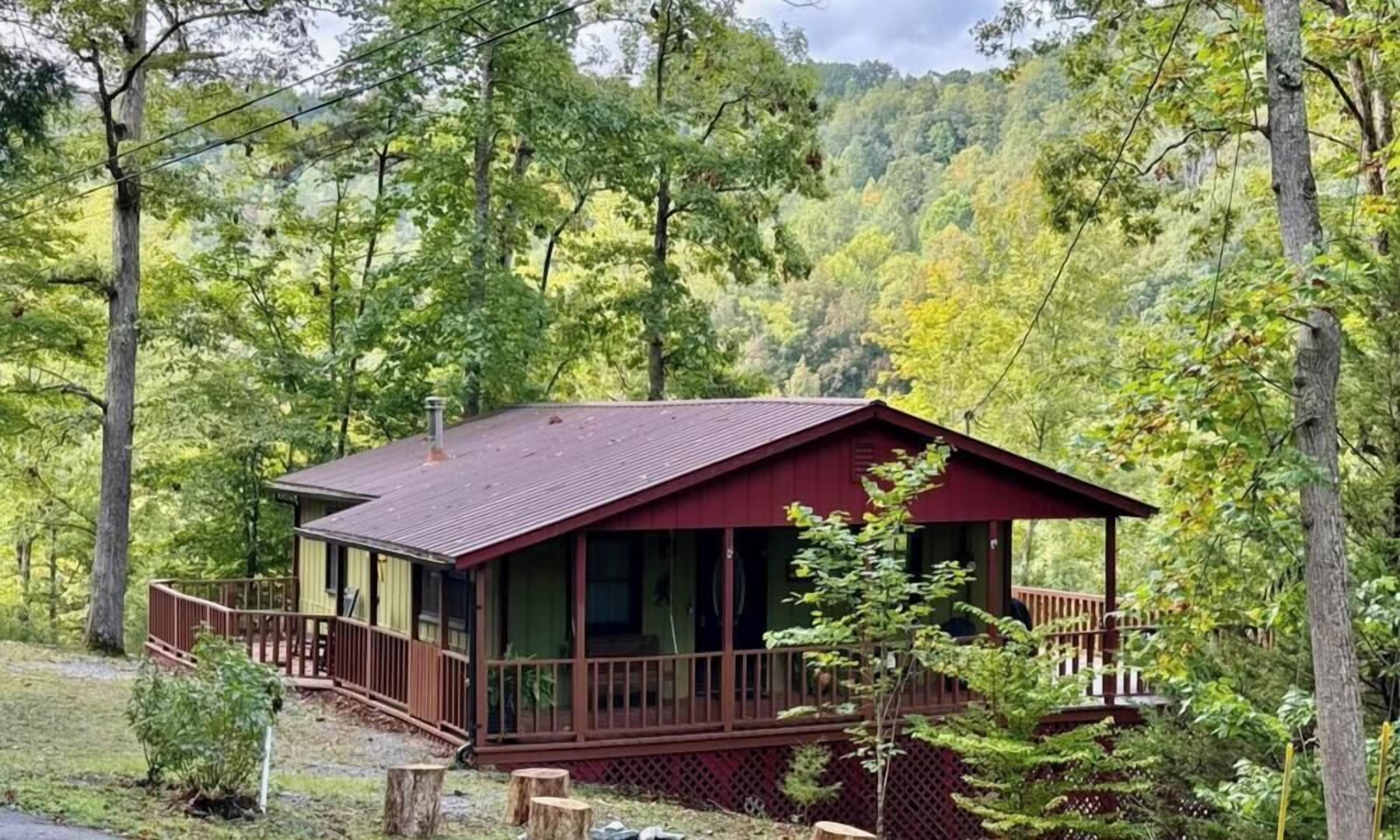 A cabin with a porch, surrounded by trees.