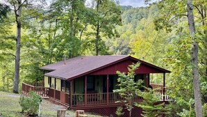 Eine Hütte mit Veranda, umgeben von Bäumen.