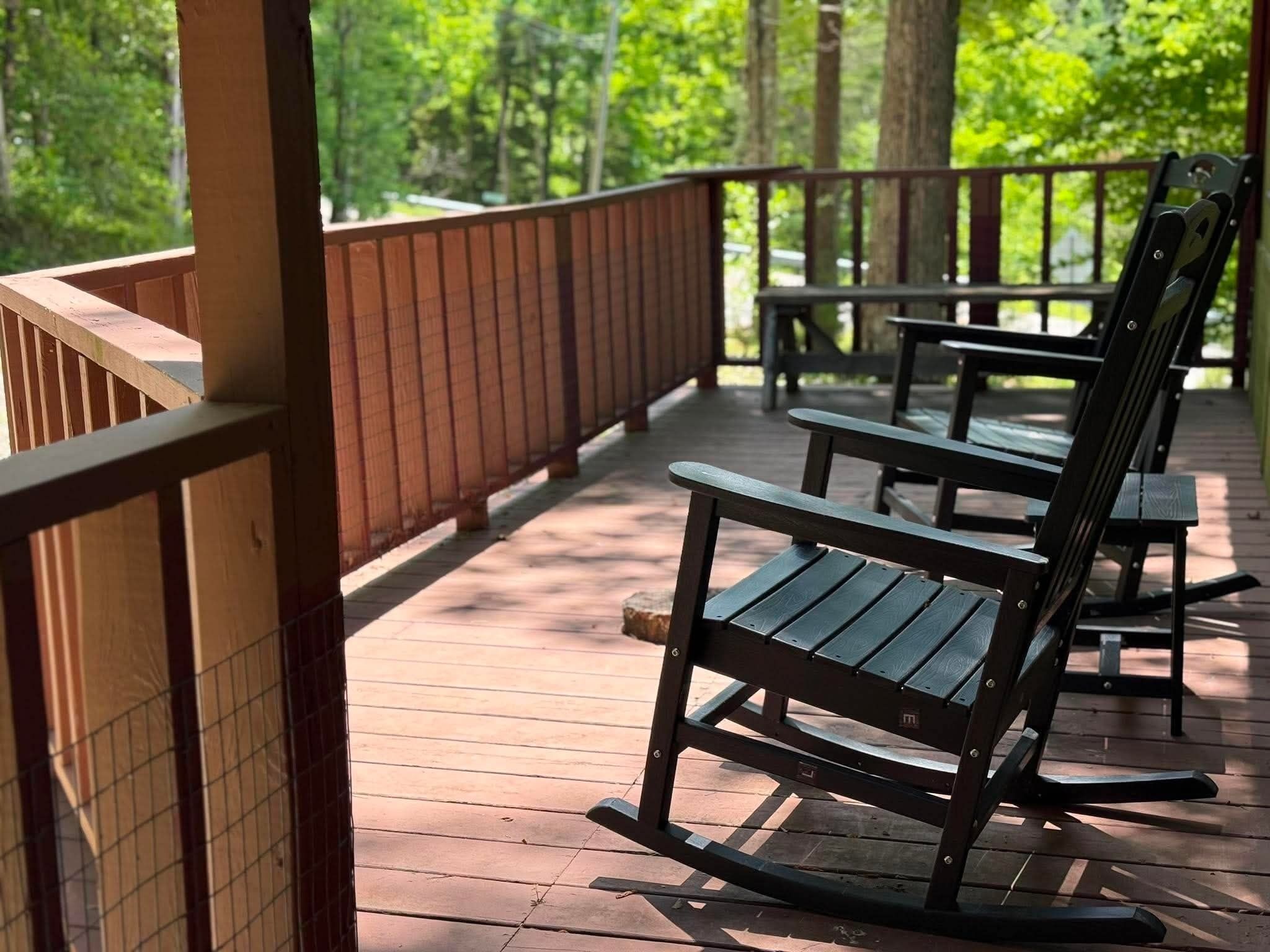 Une terrasse en bois avec une rambarde, des bancs et une vue sur une forêt.