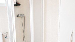 Ein modernes Badezimmer mit einer gläsernen Duschkabine, einer Toilette und einem Papierkorb.