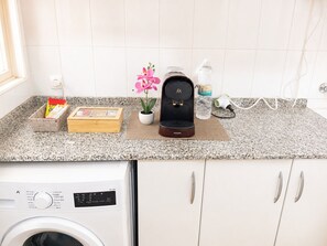 A kitchen with a coffee maker, a water bottle, a plant, and a box of tissues on the counter. - Beachfront Apartment in Los Alcázares - Murcia (Los Alcázares)