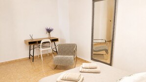 Ein Hotelzimmer mit einem Bett, einem Sessel, einem Schreibtisch und einem Spiegel.