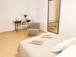 Una habitación de hotel con una cama, una silla, un escritorio y un espejo.