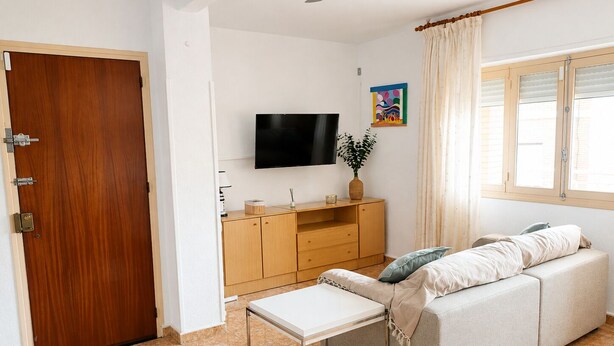 Ein Wohnzimmer mit einer Couch, einem Fernseher, einer Holzschrank und einem kleinen Tisch.