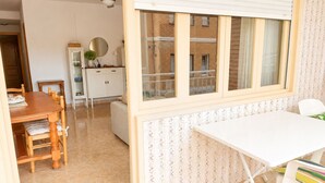 Ein Zimmer mit Esstisch, Stühlen, einem weißen Schreibtisch und einem Fenster mit Jalousien.
